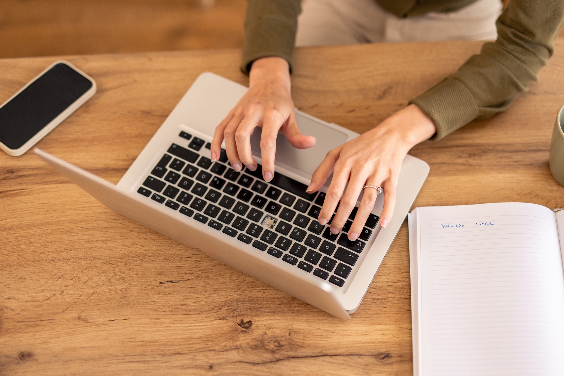 person typing on a laptop on an oak table