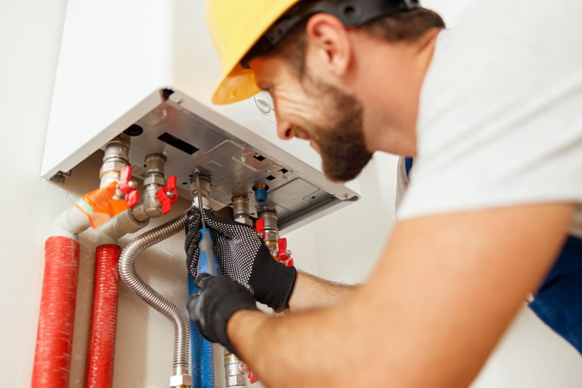 Closeup of plumber using screwdriver while fixing boiler